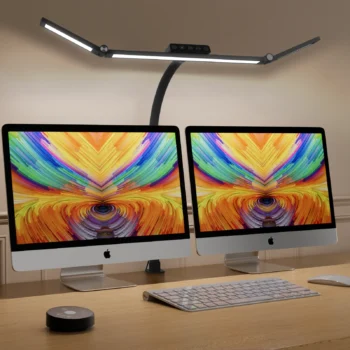 Black ultra-wide LED desk lamp illuminating a dual-monitor home office workspace